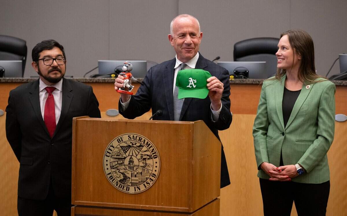Sacramento Mayor Darrell Steinberg holds a Oakland Athletics baseball cap and a River Cats bobble head doll on Thursday during a press conference about the A’s move to West Sacramento with council members Eric Guerra and Caity Maple at Sacramento City Hall.
