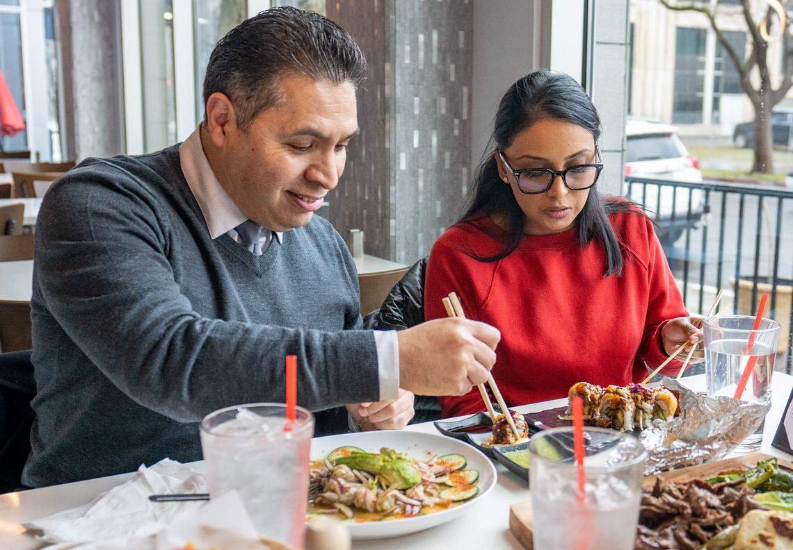 Customers Ernesto Lopez, left, and Kavita Gaunder, right, eat a Baja roll at La Capital Cuisine on Tuesday.