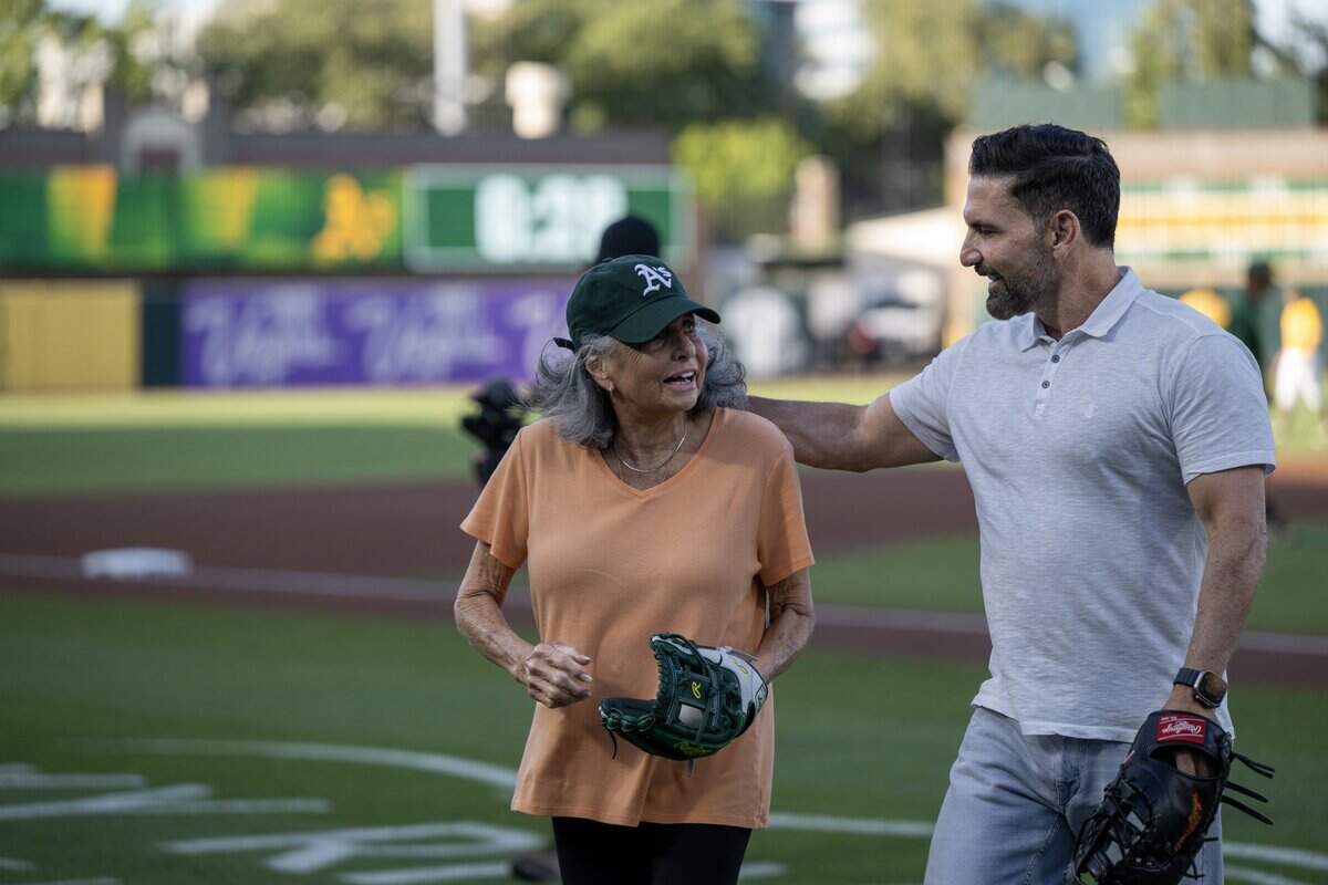 Giannina Santangelo is embraced by her son, broadcaster F.P. Santangelo, after throwing out the ceremonial first pitch before the Athletics hosted the San Francisco Giants at Sutter Health Park on Saturday.