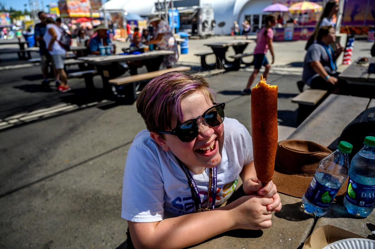 Jayne Cheshire, 10, of Stockton, enjoys her monster corn dog from Milo’s at the California State Fair on Friday, July 12, 2019 in Sacramento. Milo’s is one of the food stands that is participating with the Food Festival pass this year.