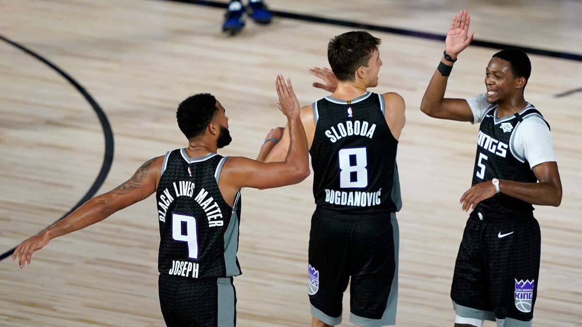Kings guards Bogdan Bogdanovic, center, De’Aaron Fox, right, and Cory Joseph celebrate Thursday during a game against the New Orleans Pelicans in Lake Buena Vista, Fla.