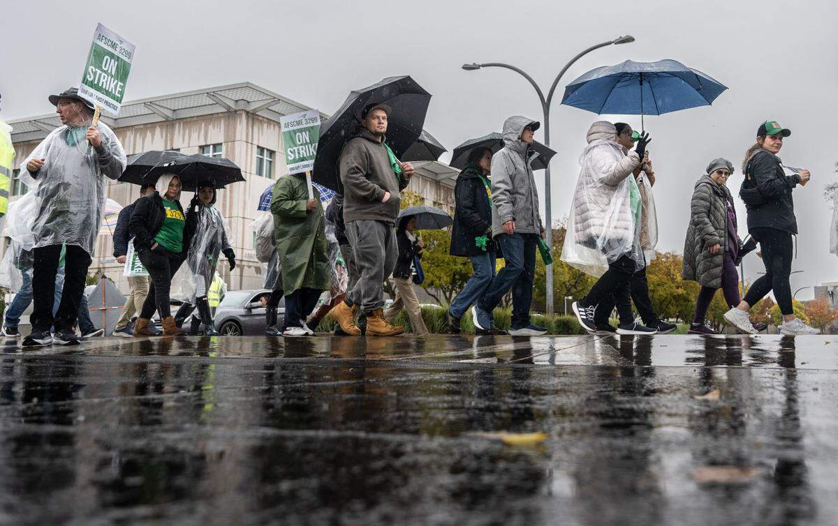 UC Davis Medical Center workers and supporters march on Wednesday, Nov. 20, 2024, in the rain at the Sacramento campus during a state wide strike by AFSCME Local 3299. The workers are asking for higher salaries and aa stop to an increase to their medical insurance.