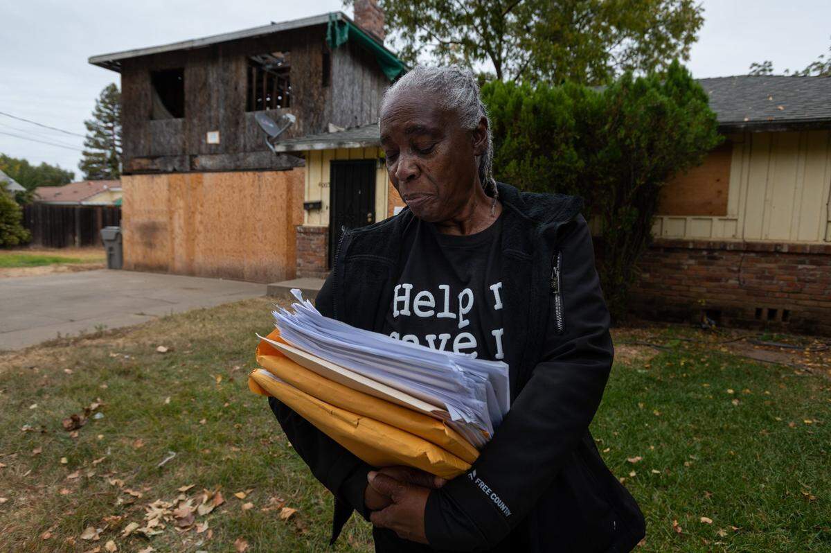 Wanda Clark holds a stack of legal papers in October in front of her Oak Park home that was placed in receivership after the city sued her for not completing a construction project. She said she paid a contractor $35,000 up front but he did not finish the work. The home was demolished in January.