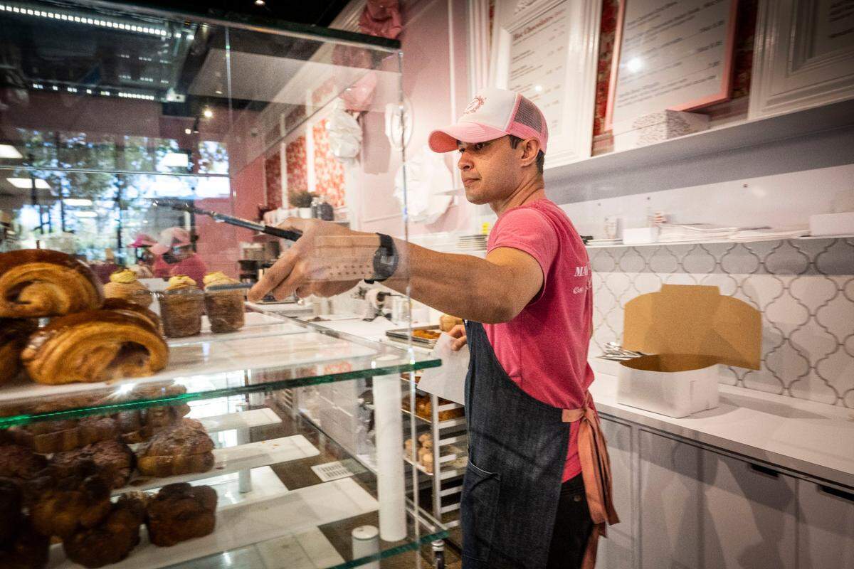 Joel Fischer, an employee at Ginger Elizabeth Patisserie, helps a customer on Tuesday. Owner Ginger Elizabeth Hahn said she has increased wages 25-30% across all positions over the past two years at her two midtown Sacramento shops.