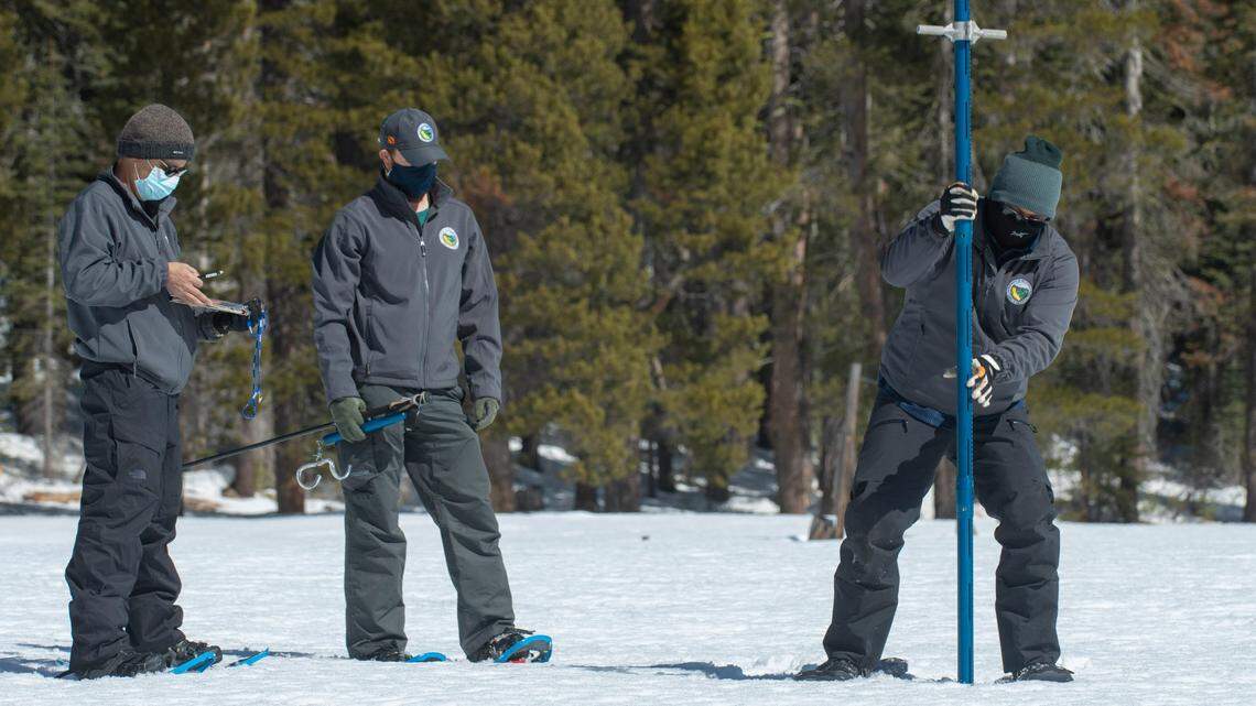 Assisted by Ramesh Gautam, left and Anthony Burdock, Sean de Guzman, right, chief of snow surveys for the California Department of Water Resources, checks the depth of the snowpack during the second snow survey of the season at Phillips Station near Echo Summit on Tuesday, March 2, 2021. The survey found the snowpack at 56 inches deep with a water content of 21 inches.