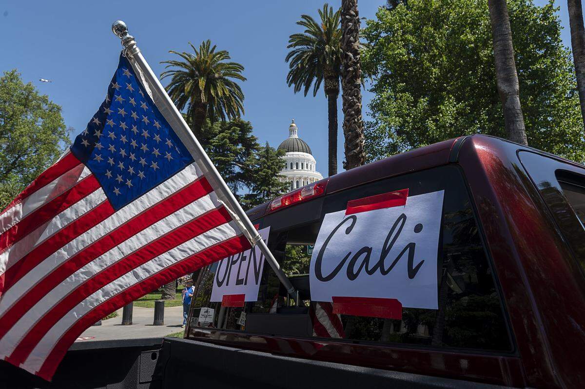 Protesters drive down N Street as they demonstrate at the Capitol in Sacramento on Friday, May 1, 2020, against Gov. Gavin Newsom’s stay-at-home order to slow the spread of the coronavirus.