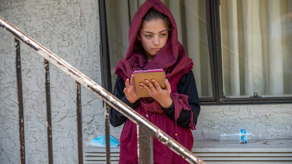 Behind a worn banister at Americaís Best Value Inn in North Highlands, Afghan refugee Zulaikha, 13, plays on a tablet on Wednesday, Aug. 25, 2021, two days after arriving in the United States. Her father Abdul said the family will enroll their children in school once they are vaccinated.