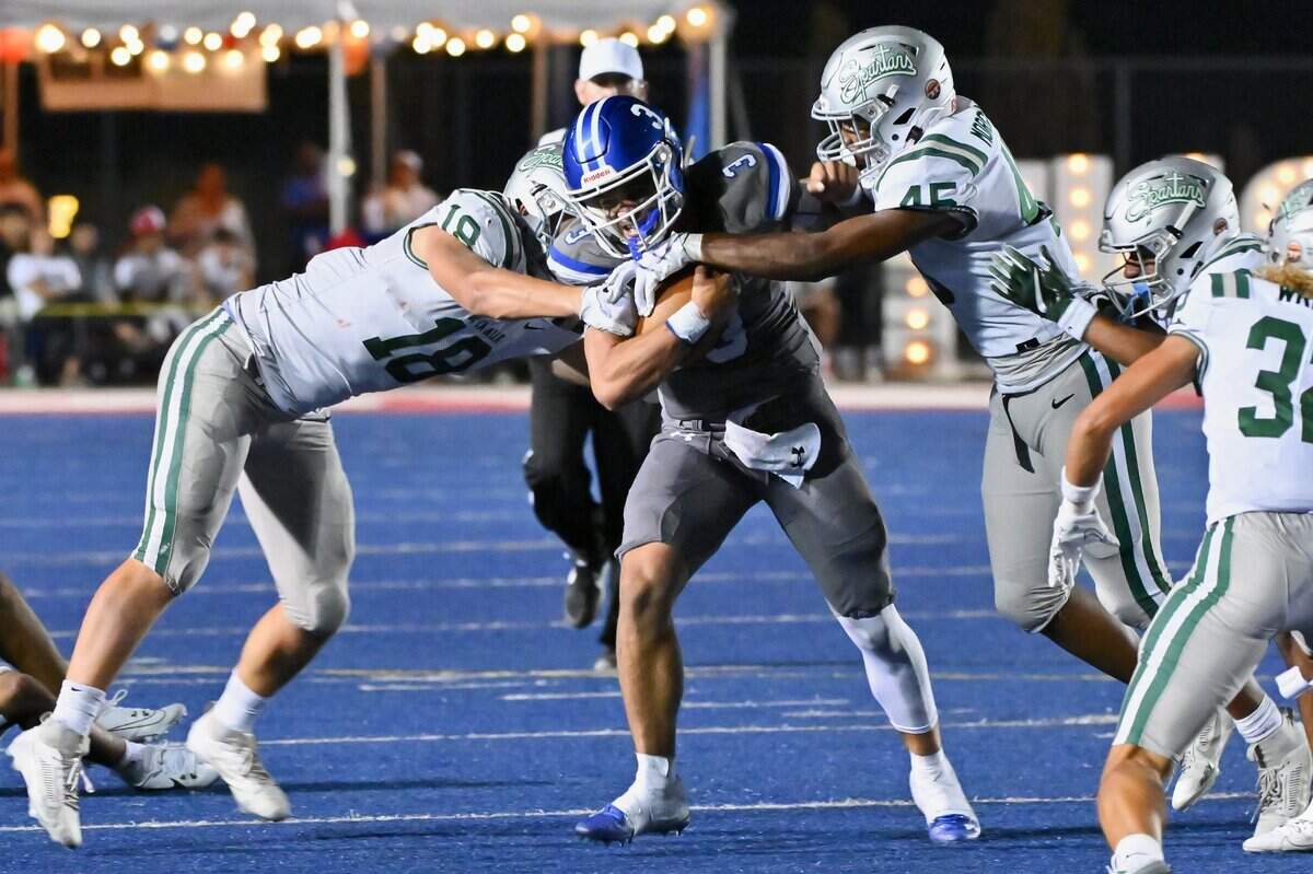 Folsom Bulldogs quarterback Ryder Lyons (3) runs the ball for a first down with the De La Salle Spartans’ Andrew Cunningham (18) and Anthony Morgan (45) putting pressure on him in the second half of the game on Friday, Sept. 22, 2023, at Folsom High School in Folsom