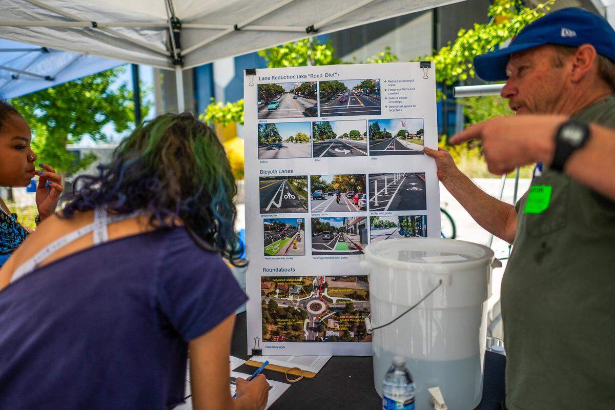 Josh Meyer of the nonprofit Civic Well explains renderings showing proposed improvements to Dewey Drive as Del Campo High School students sign a petition during the “Slow Down Dewey” event at the Carmichael school on Thursday, May 7, 2026.