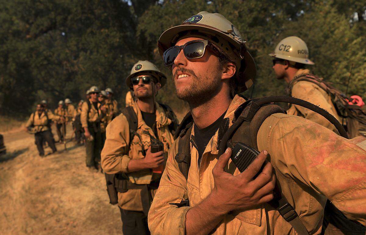 Ventura County firefighters including Caleb Amico, foreground, watch as a helicopter makes a drop on a hot spot of a wildfire in Scotts Valley near Lakeport, Calif., Friday, Aug. 3, 2018. (Kent Porter /The Press Democrat via AP)