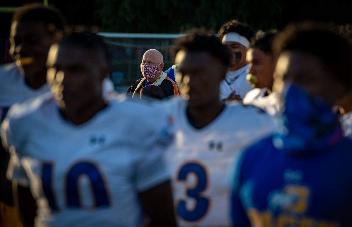 Grant High School head coach Mike Alberghini wears a mask as he stands with his team for the national anthem on Friday, April 16, 2021, as the Pacers played their final game of a coronavirus-shortened spring season against Capital Christian High School in Rancho Cordova.