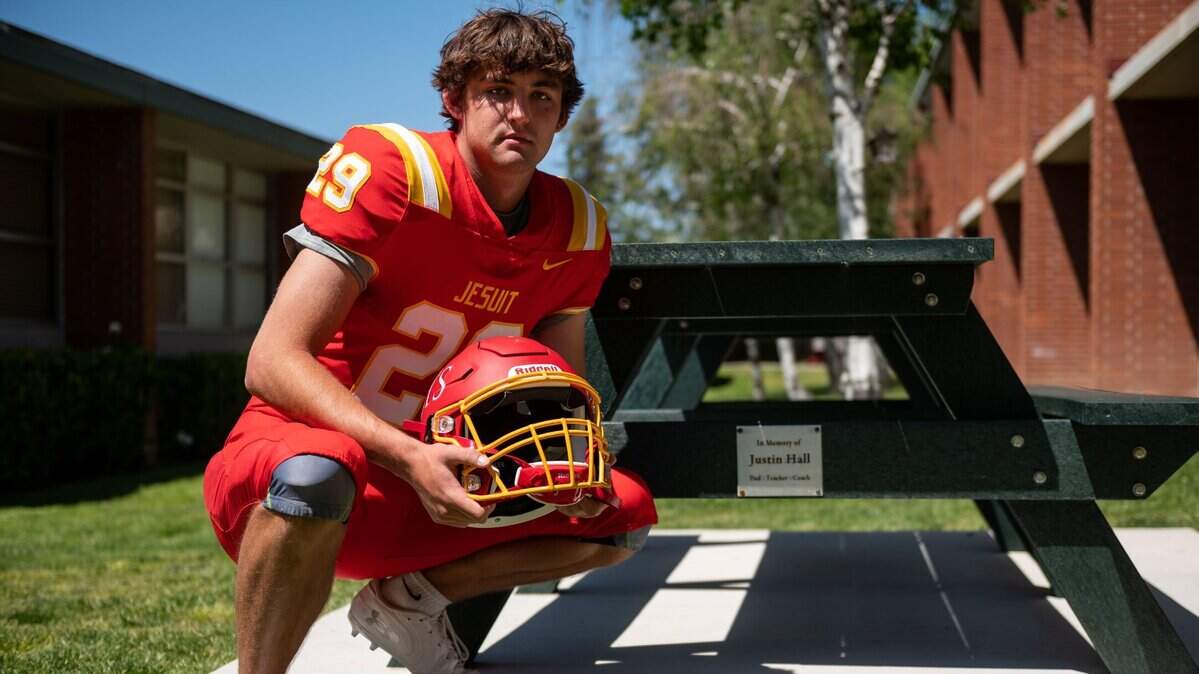 Jesuit High Schools Jacob Hall has had numerous injuries that have sidelined him at the end of his high school football career. His father, Jesuit teacher and coach Justin Hall, suffered from chronic traumatic encephalopathy, or CTE, caused by concussions during his football career which including college at Notre Dame. The neurodegenerative disease culminated in his suicide four years ago. Moments before their game against Vista del Lago on Saturday, April 17, 2021, Jake shows a table that honors his father on campus at Jesuit High School in Carmichael.