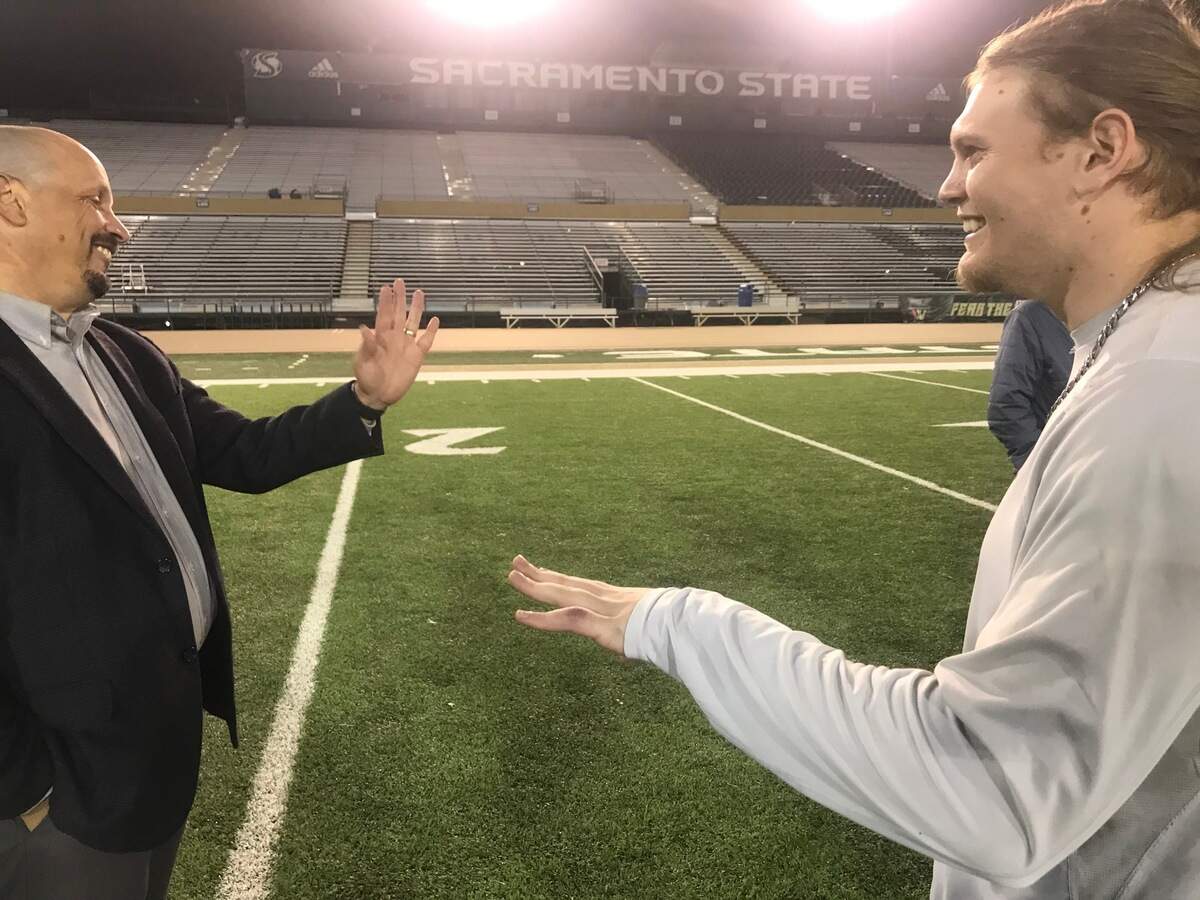 Sacramento State athletic director Mark Orr compares mangled fingers with Sacramento State linebacker Marcus Hawkins in November, 2021.
