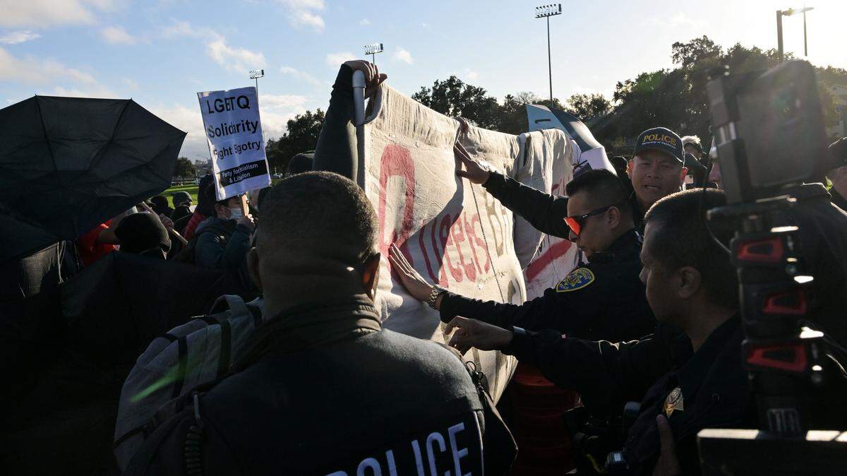 University of California police push back a sign held by protesters outside the U Center before an appearance by Charlie Kirk, founder of the conservative nonprofit Turning Point USA, on Tuesday, March 14, 2023, at UC Davis. A previous TPUSA presentation Oct. 25 was canceled after clashes between protesters and counter-protesters.