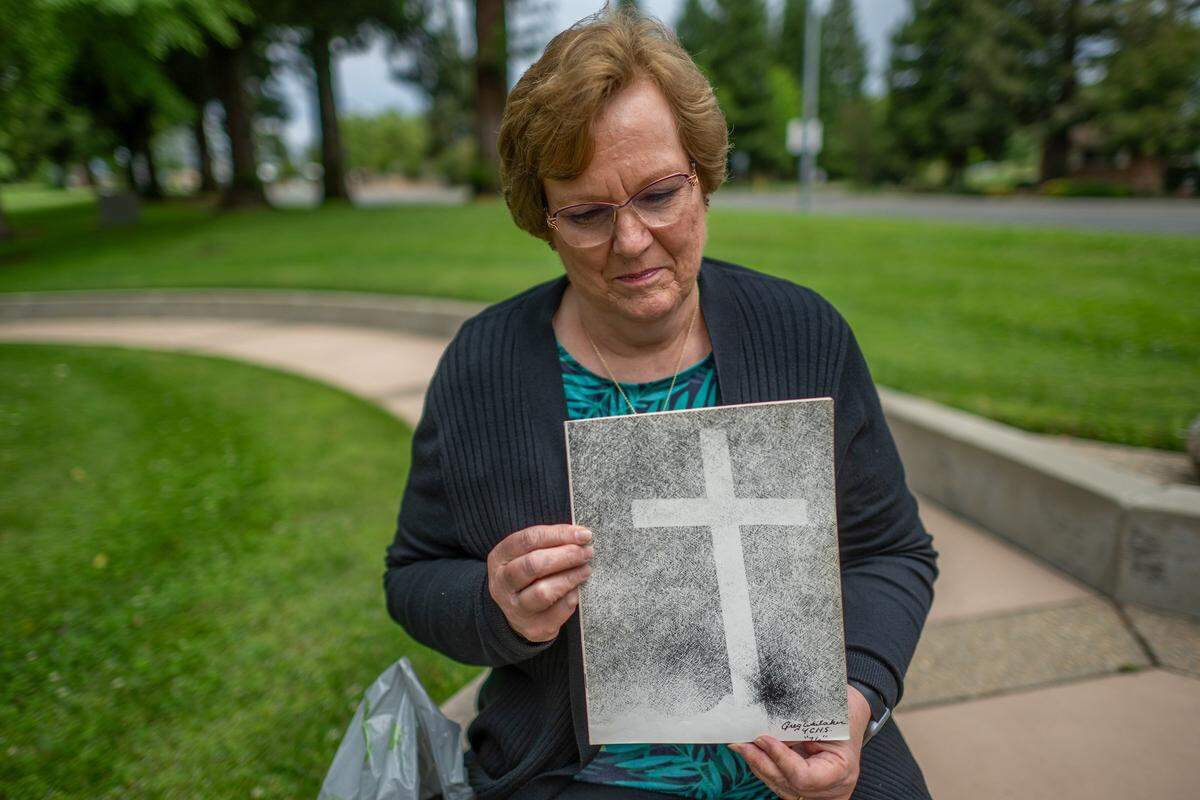 Donna Peacock Sorenson, a survivor of the 1976 bus crash that killed 28 Yuba City High School choir students and a music teacher, holds a yearbook supplement that was made after the crash while standing at a memorial site for victims and survivors in Yuba City on Monday. “I like to come here every year, or whenever I can, to remember — not necessarily the horrible events of the day, but to remember those we lost and how people are affected,” Sorenson said.