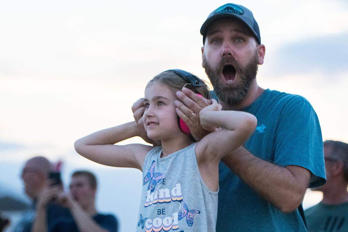 Jonathan Rihel, back, covers his 6-year-old daughter Gwen’s ears while watching an F-35 fighter jet during the California Capital Airshow at Mather Airport near Rancho Cordova on Saturday, July 13, 2024. While Gwen Rihel’s favorite part of the day was the snowcone she had, Jonathan Rihel said he most enjoyed seeing Frecce Tricolori’s performance because of how many planes the Italians had.