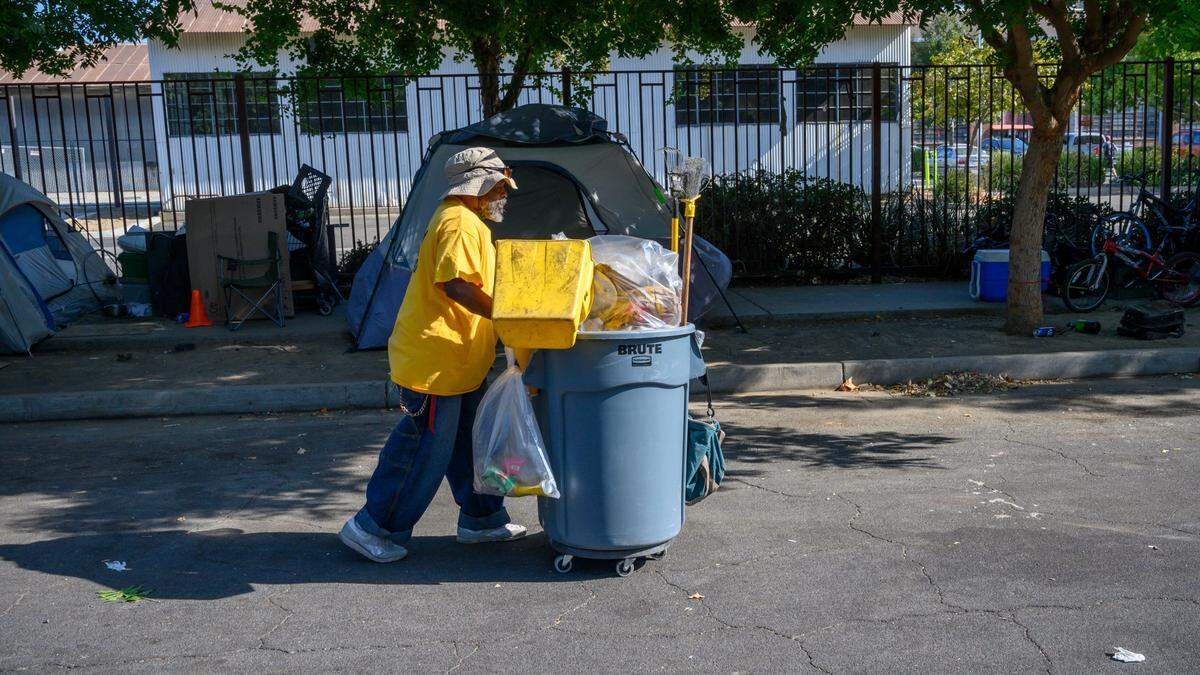 David Jones with the Downtown Streets Team picks up trash near a lot where the city is exterminating rats in preparation to build a fire station, Friday, Sept. 6, 2019.