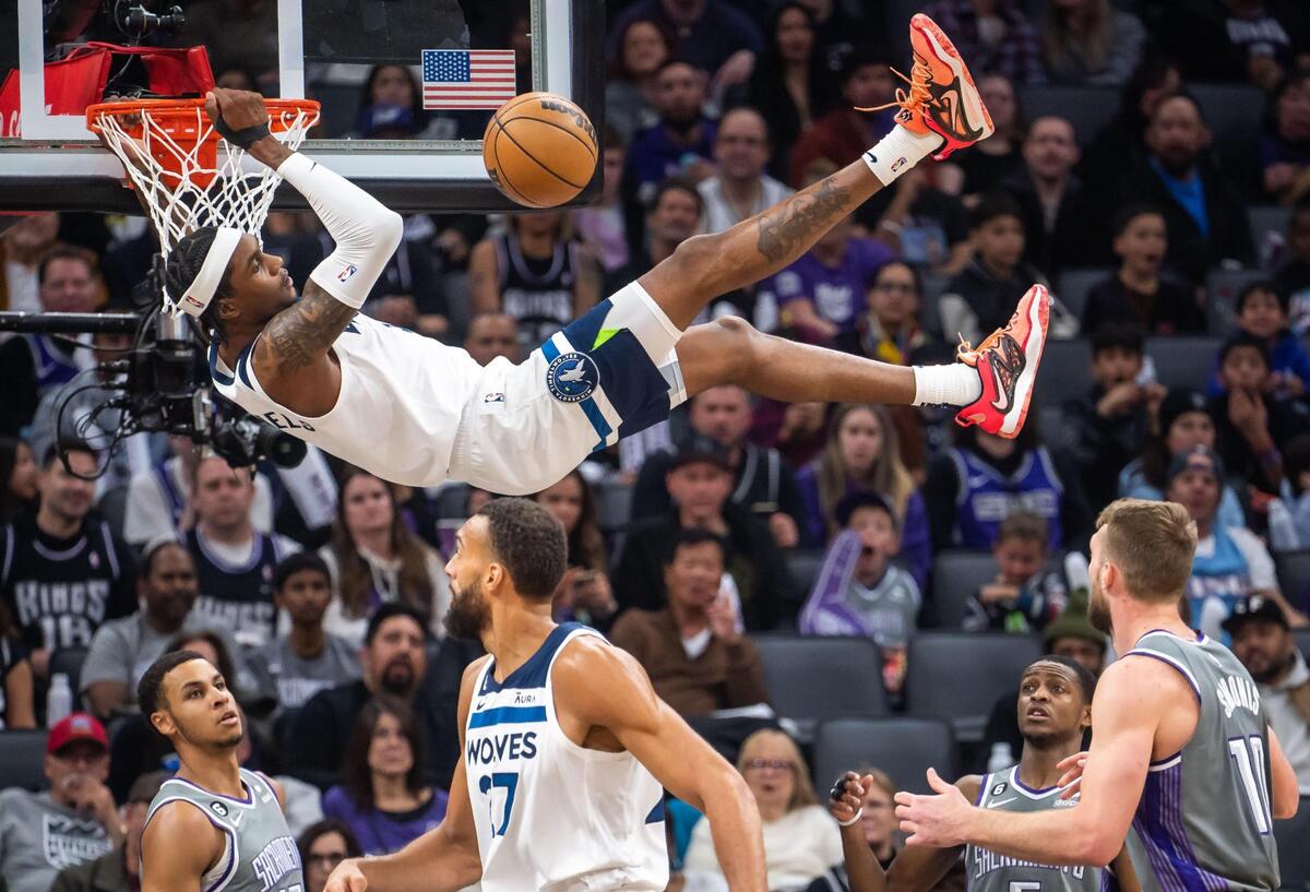 Minnesota Timberwolves forward Jaden McDaniels (3) holds on to the rim after missing a slam dunk and getting called off an offensive foul as Sacramento Kings guard De’Aaron Fox (5), right, and forward Keegan Murray (13) stand nearby during the second quarter of the NBA basketball game Saturday, March 4, 2023, at Golden 1 Center in Sacramento.