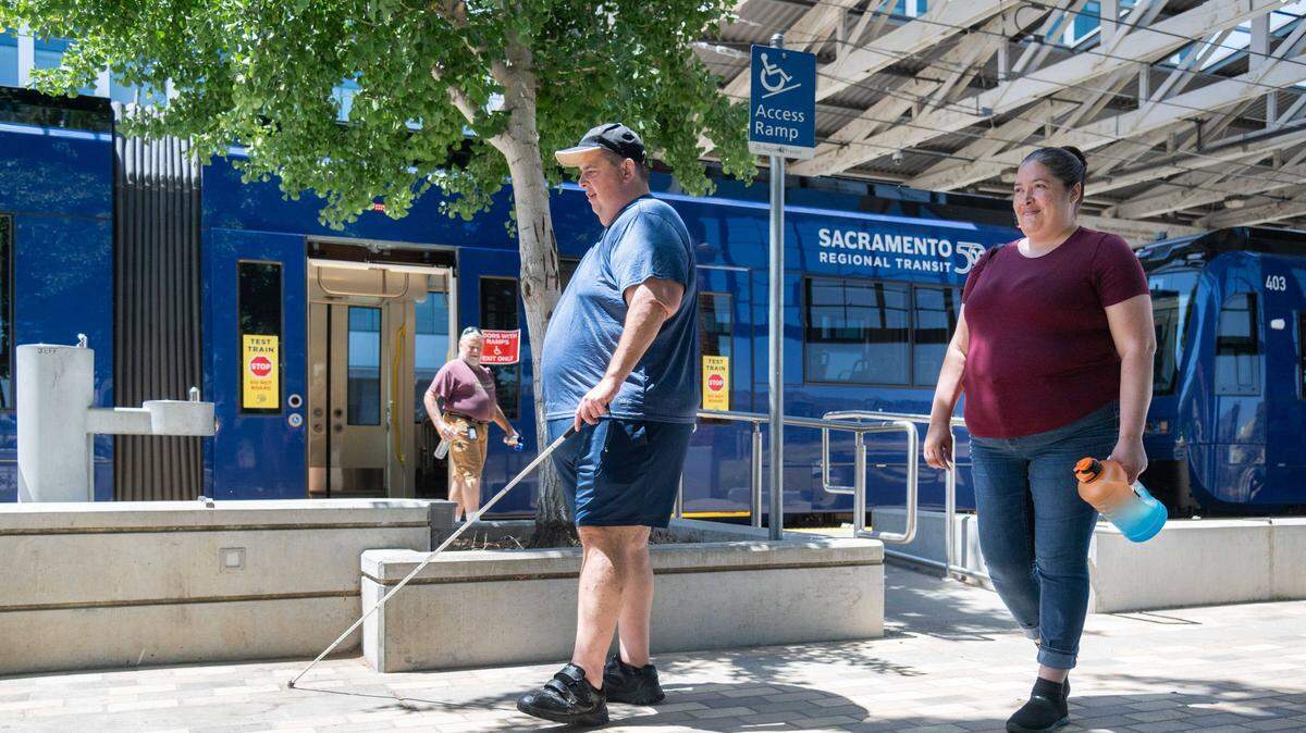 Rick Hodgkins, who is visually impaired, and Alexandria Mendibles exit a new S700 low-floor light rail train using an access ramp at the Township 9 station in Sacramento in 2024. Regional Transit's light rail is one of several transit options in the Sacramento area that MetroHub staff can help riders navigate as part of a broader effort to make capital region transportation more accessible.