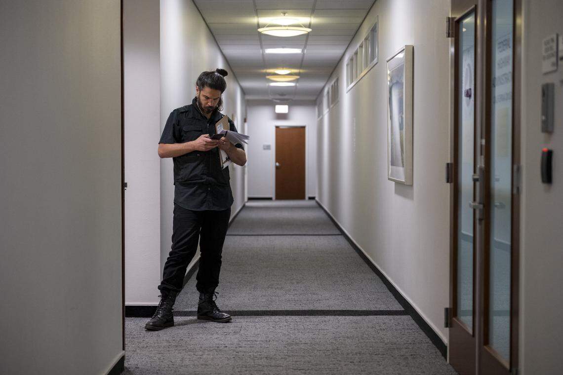 Niko Volonakis stands in an empty hallway of the the John E. Moss federal building in downtown Sacramento while sending a text message to other court observation volunteers during immigration court hearings in downtown Sacramento on July 22.