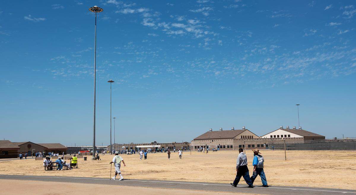 Inmates walk across the grounds of Valley State Prison in Chowchilla in July 2021. Proposition 57 gave some inmates early parole opportunities and more chances to shave down their sentences through credit-earning.