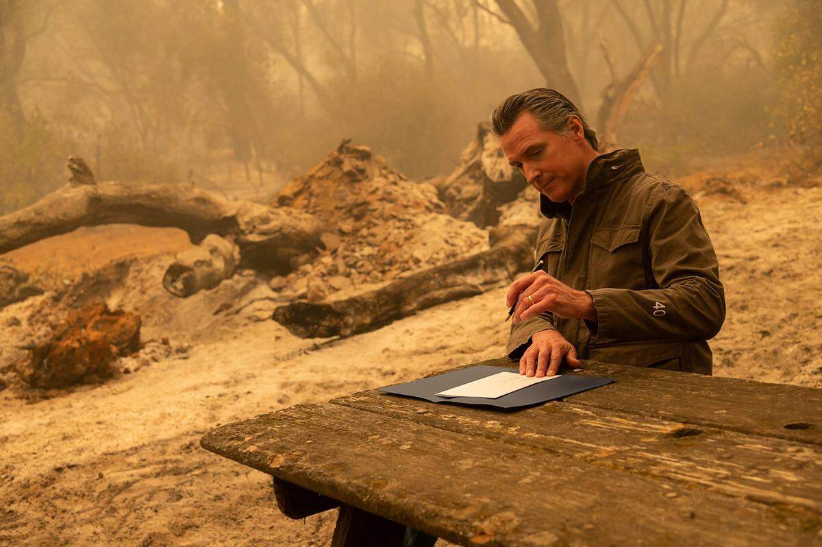 Gov. Gavin Newsom signs AB 2147, which allows members of inmate fire crews to become firefighters after their sentence is served, after touring the North Complex Fire zone near Oroville in Butte County in September 2020.