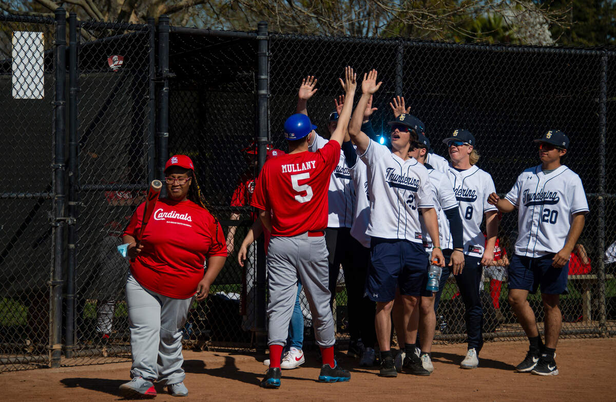 Faith Allen steps up to bat on March 6 as Zach Mullany (5) is congratulated by members of the Elk Grove High School baseball team after he returns from scoring a run.