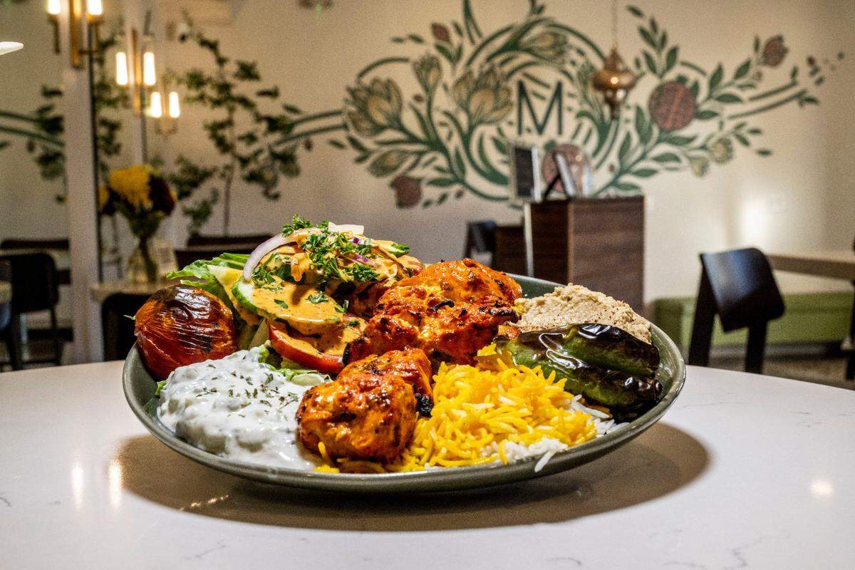 A Taste of Maydoon plate which includes chicken served with mixed greens, must khiar, hummus, pita and rice on Thursday, Nov. 17, 2022. The Persian restaurant will open during its normal business hours on Christmas Eve, Dec. 24, 2025.