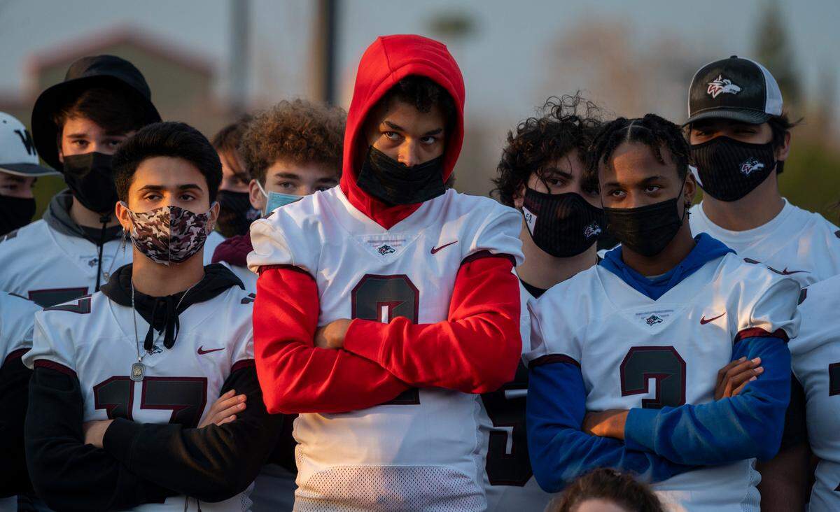 Woodcreek High football teammates and cousins, Amari Taylor, 17, center, and Dashawn Bradley, 16, center right, stand with fellow athletes and parents during a “Let Them Play” rally in Rocklin, one of a series of rallies across California on Friday, Jan. 15, 2021, to push for the resumption of high school sports during the coronavirus pandemic.