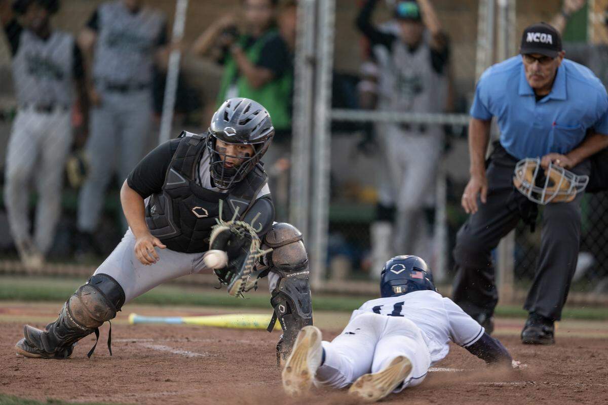 The Elk Grove Thundering Herd's Tristen Bartlett slides past the Rodriguez Mustangs’ Nateo Victorio on Thursday in the CIF Sac-Joaquin Section Division II baseball championship at Sacramento City College.