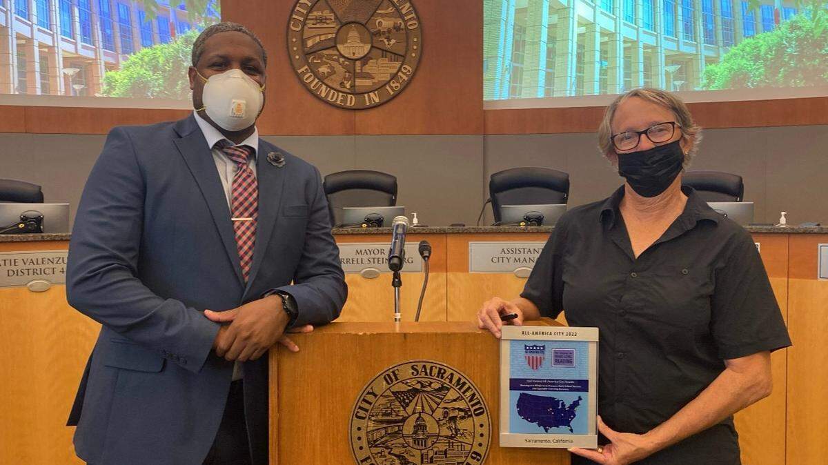 On August 23, 2022, Julius Austin (left) Sacramento Promise Zone coordinator, posed with April Jarvist (right) Executive Director of Sacramento Literacy Foundation as she holds the 2022 National Civic League All-American City Award.