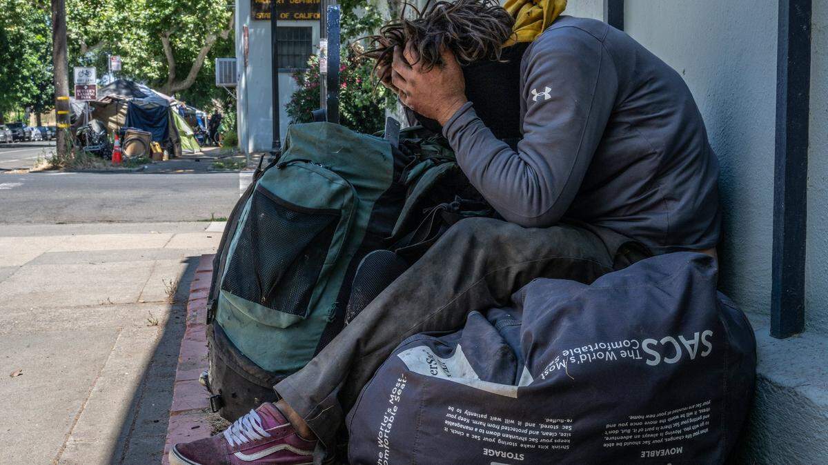 Homeless camper Chadwick Justin Foy, 41, right, says he has no idea where he will move while resting in the shade at the intersection of 28th and C streets on Tuesday, July 18, 2023. The city has given notices to dozens of people living in tents on the sidewalks in that area, near Leland Stanford Park, telling them to move by Wednesday. The notices cite violation of city codes regarding sidewalk obstruction and storage of personal property on public property.