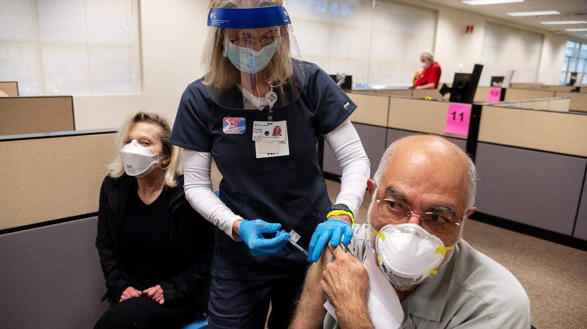 Registered nurse Theresa Frei, who is the chief executive officer of the Sutter Medical Foundation, administers the Pfizer COVID-19 vaccine to Nasser Kamili, 72, and Rebecca Kamdi, 66, during a large-scale vaccine clinic by Sutter Health on Thursday, Feb. 4, 2021 in Sacramento. Sutter is vaccinating 800 seniors and healthcare workers with their first doses of the vaccine.