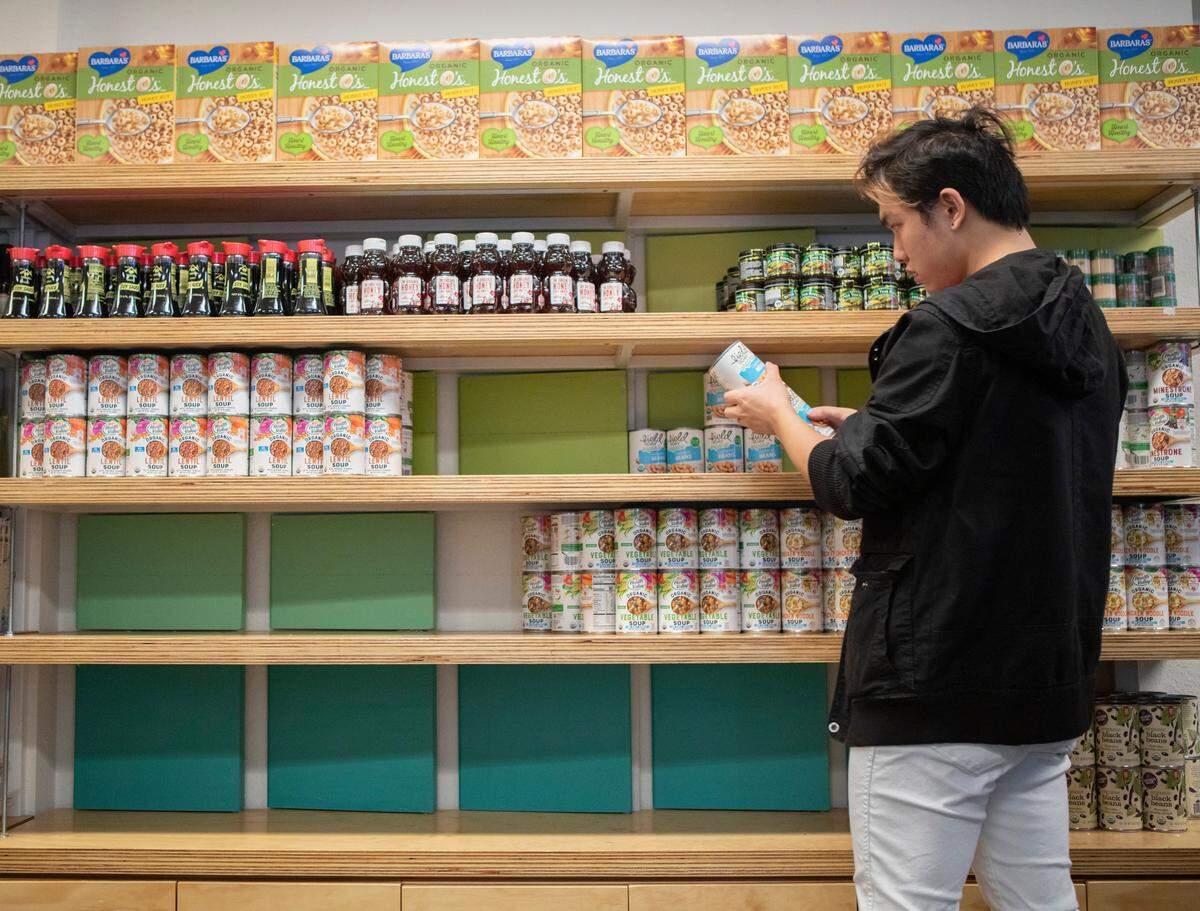 Student volunteer Yongjie He restocks shelves with canned goods at the UC Berkeley campus food pantry.