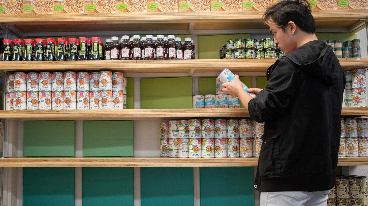 A student volunteer restocks shelves with canned goods at the UC Berkeley campus food pantry.