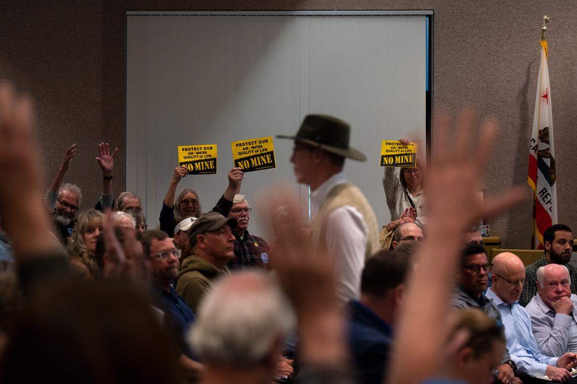 Members of the public hold up “no mine” signs, while others wave their hands in the air in silent applause, as a man who spoke against the Idaho-Maryland Mine during public comment walks back to his seat on May 11 during the second day of the Nevada County planning commission hearings on the project. The commission later voted unanimously against the mine. 