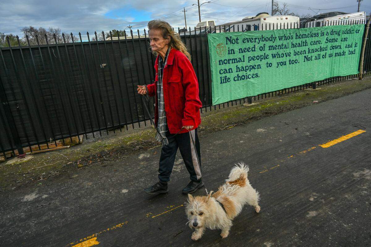 Ruby Stonebraker, 73, and her dog walk along the bike trail next to Arden Way in North Sacramento on Monday to survey the damage to her tent after a tree fell on it the night before while she was inside.