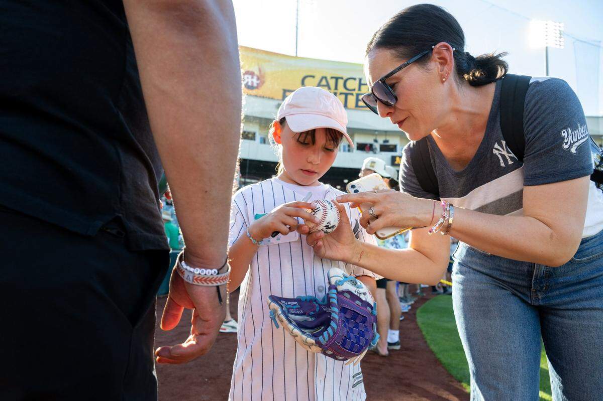 New York Yankees fan Maria Lugo, of Elk Grove, looks at the seven autographs her daughter, Victoria, 7, collected on her ball and glove before the New York Yankees and Athletics game at Sutter Health Park on Friday, May 9, 2025, in West Sacramento. 