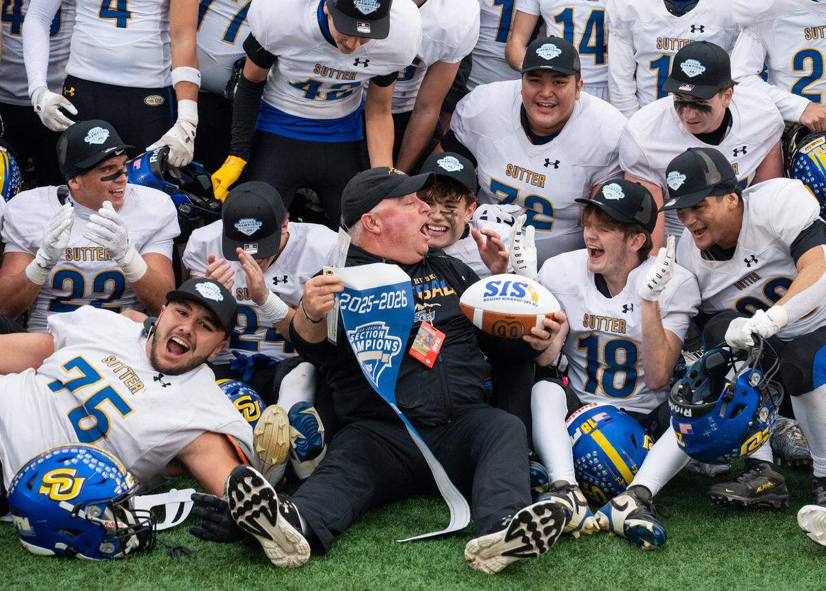 Sutter Huskies coach Ryan Reynolds shares a moment with player Brody Spencer (18) as he holds the CIF Sac-Joaquin Section Division V championship pennant after defeating the Casa Roble Rams 42-27 at Hughes Stadium in Sacramento on Friday, Nov. 28, 2025.