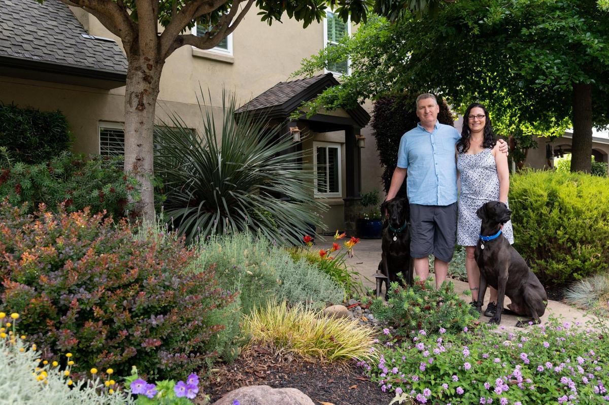 Jeff and Desiree Cherye stand with their dogs, Hank and Clyde, in their drought-tolerant designed front yard in Sacramento earlier this month. They made the choice to remove their front lawn and replace it with drought-tolerant plants and an edible garden in their back yard.