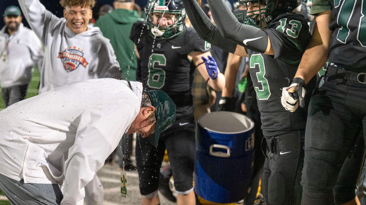 The Twelve Bridges Raging Rhinos’ Joseph Alkhudr (13) pours a little extra water on coach Chris Bean as he recovers from an ice water bucket dump on the sidelines as the clock winds down on team’s victory in the Sac-Joaquin Section Division IV championship game on Nov. 29, 2024, at Hughes Stadium in Sacramento. The Bee’s Coach of the Year last season, Bean again finds himself among the candidates for this season’s honor. 