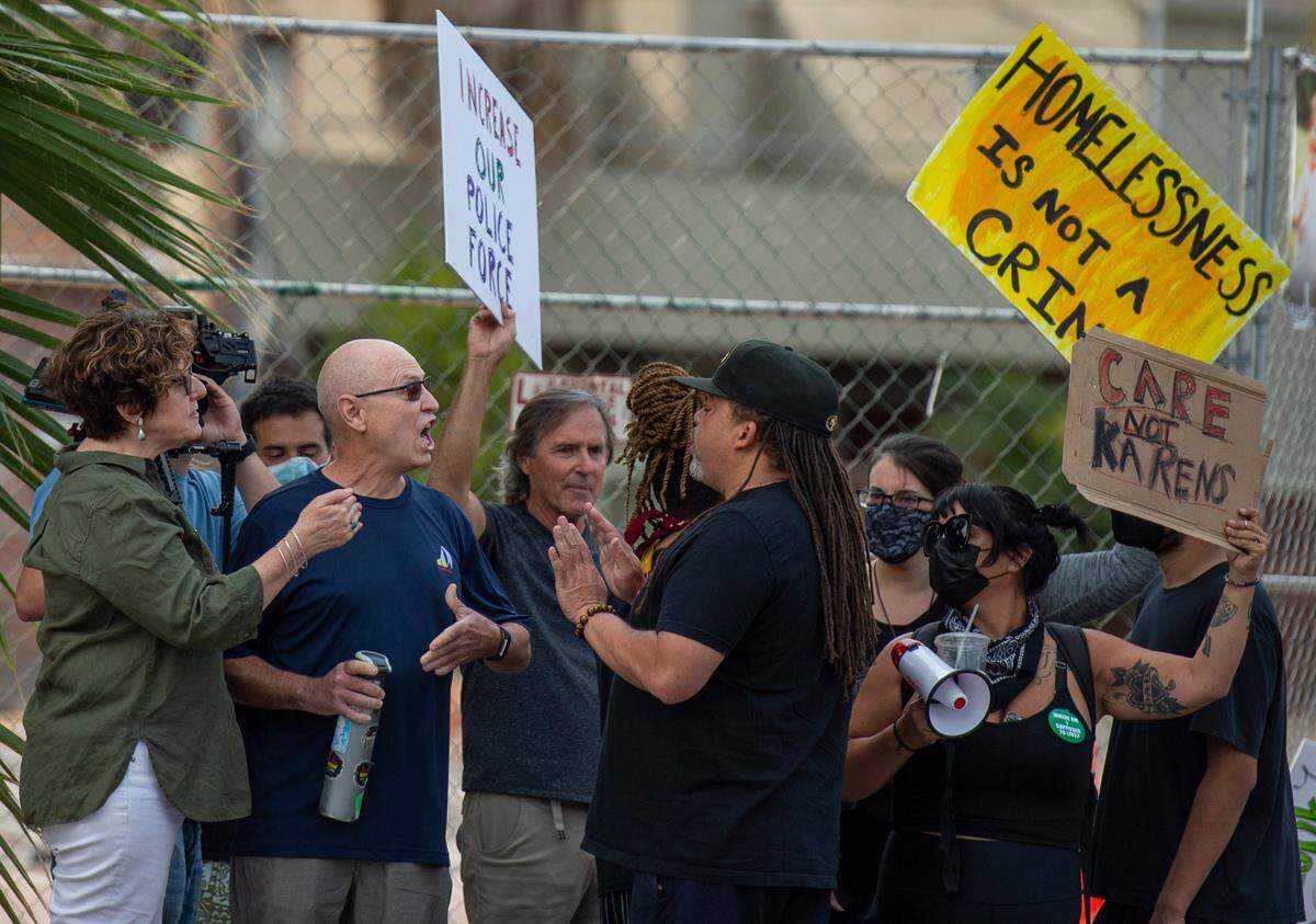 Adam Jordan, center, of the Anti Police-Terror Project, speaks with a man after crossing the street to the group advocating increased policing as two protests faced off on Broadway about police funding and homelessness in Sacramento.