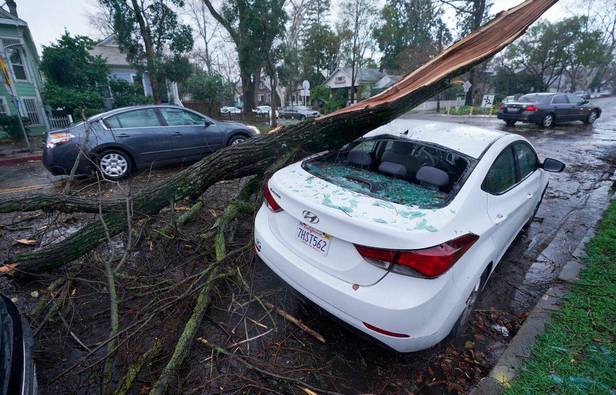 A car sustained damage when a tree limb fell on it during an overnight storm that swept through Sacramento, Calif., Wednesday, Jan. 27, 2021.
