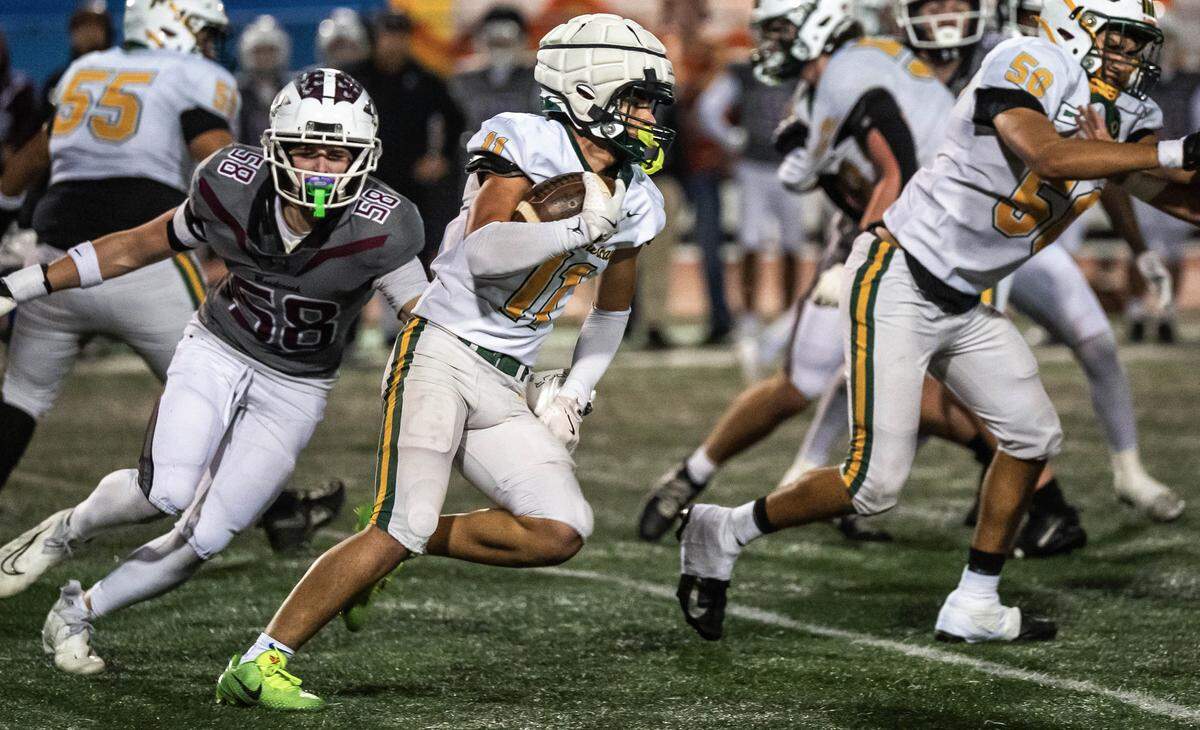 Rio Americano Raiders running back Niko Chatzis (11) carries the ball upfield past Woodcreek Timberwolves defensive end Brody Kee (58) in a CIF Sac-Joaquin Division III semifinal playoff game in Roseville on Friday, Nov. 21, 2025. 
