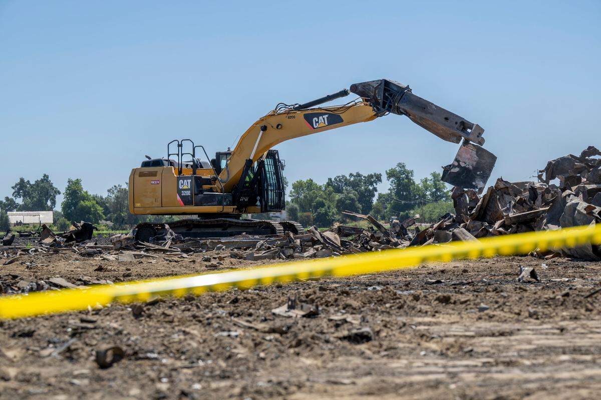 An excavator cuts debris from the Devastating Pyrotechnics explosion in a nearby field in Esparto in July.