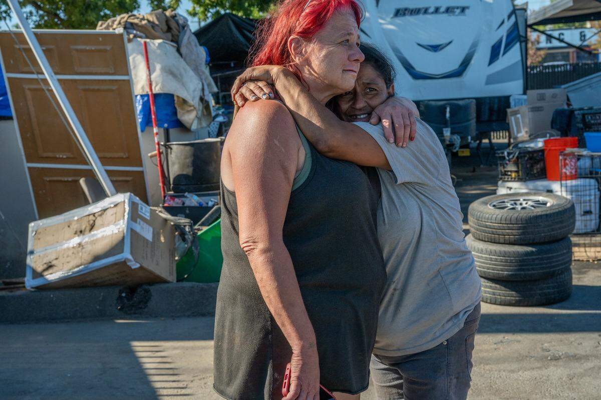 Twana James, left, hugs another resident of Camp Resolution as the Sacramento fire marshal arrives to reinspect the homeless encampment on Friday.