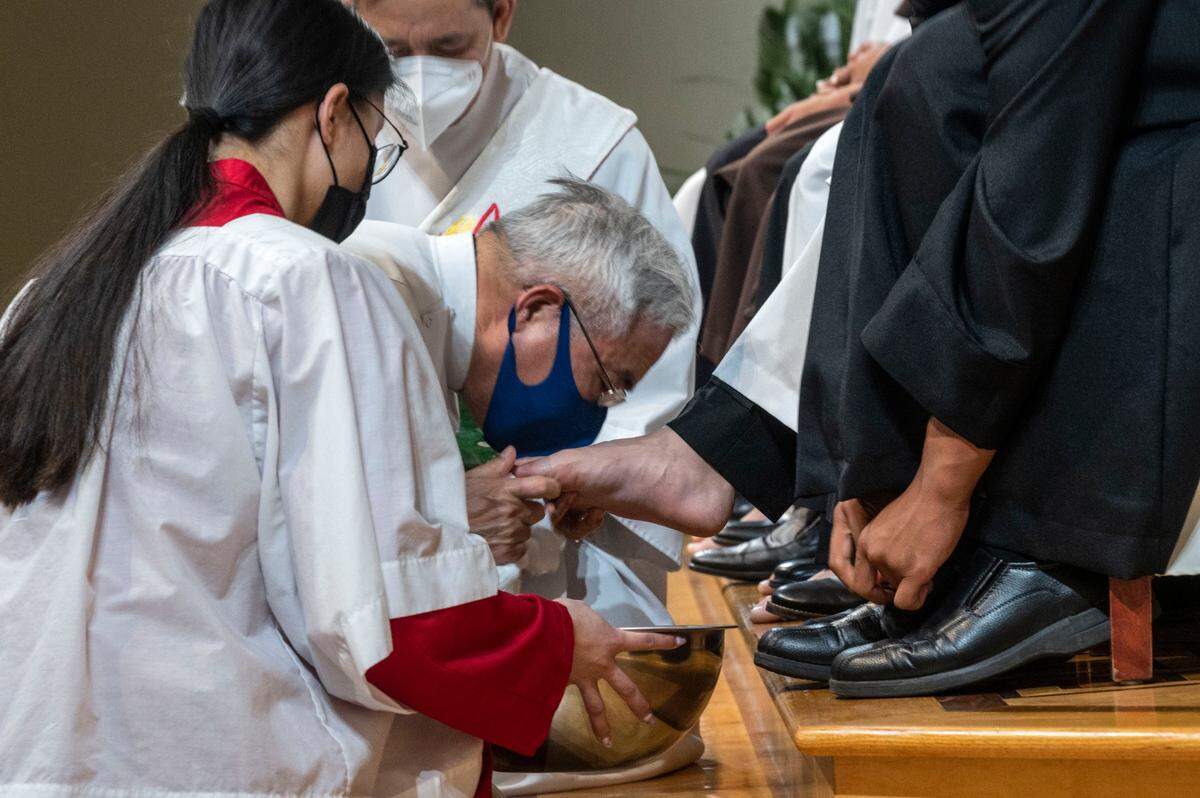 Pastor Louis Nhien kisses the feet of one of the young men who represented the 12 apostles as members of the Vietnamese Martyrs Parish in south Sacramento celebrate Holy Thursday with a mass and eucharistic adoration.