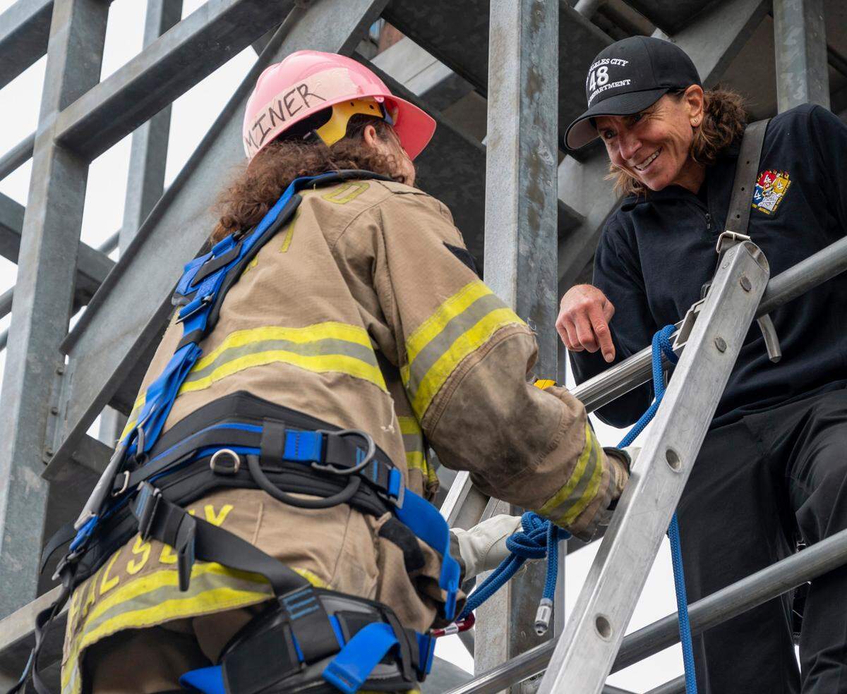 The Los Angeles Fire Department’s Tami Chick, waits at the top of the ladder in the “towerî”and smiles as Alexandria Miner, 16, of Sacramento, climbs at the Sacramento Area Girls Fire Camp at McClellan Park in October. The tower was brought in the day before to be used for drills for this camp.