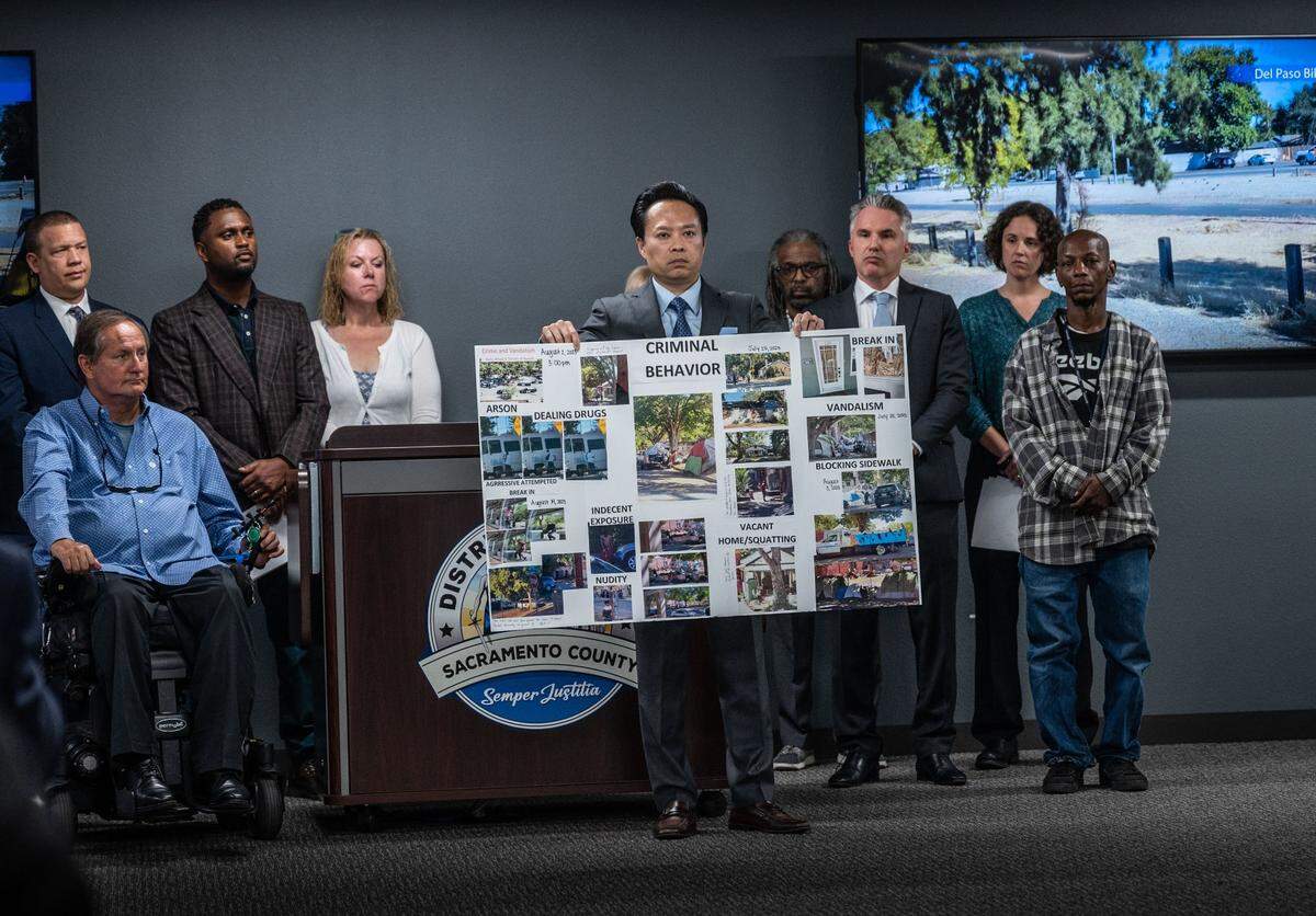 Sacramento County District Attorney Thien Ho holds a poster collage titled “criminal behavior” as he announces Tuesday that his office is suing the city of Sacramento for creating a public nuisance by failing to take stronger action on homeless camps.