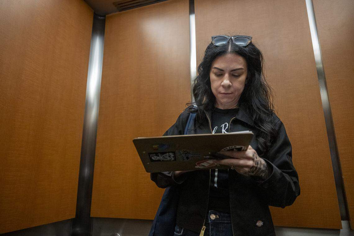 Heidi Phipps takes notes on a clipboard inside of elevator after escorting a family out of the John E. Moss federal building in downtown Sacramento from immigration court on July 24.